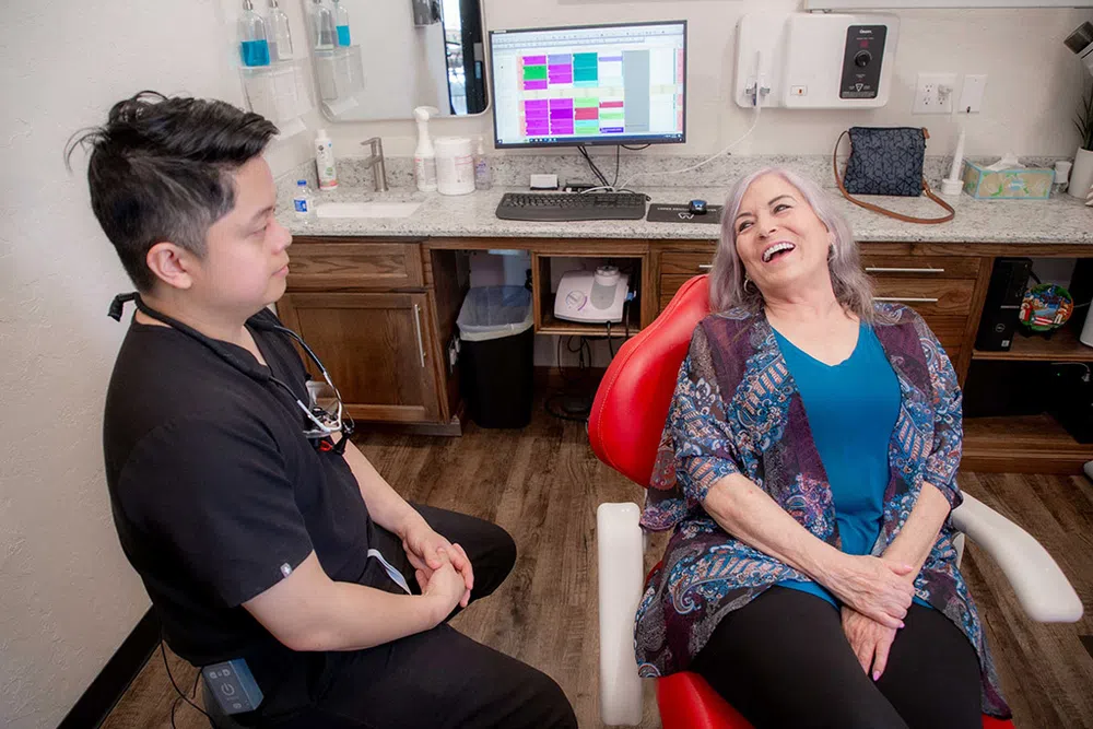 Dentist consulting with a smiling elderly woman seated in a dental chair in a modern clinic.