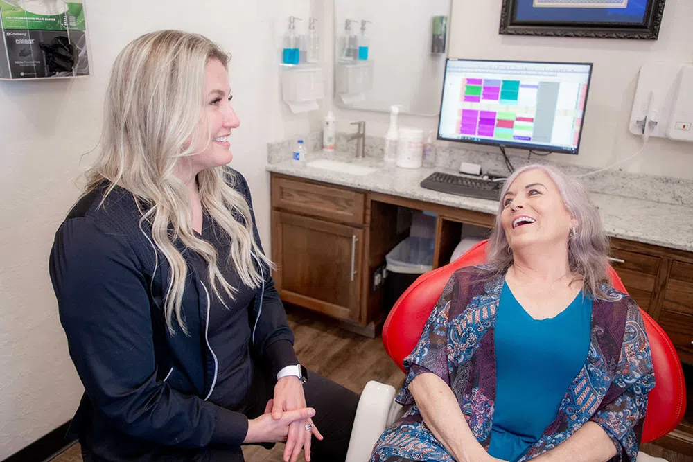 Smiling female dentist or hygienist talking with a happy older female patient in a dental office.
