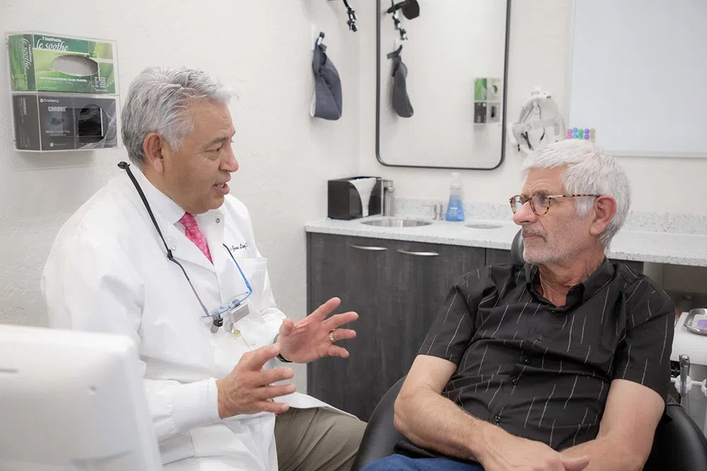 Doctor in white coat discussing treatment with elderly male patient in medical consultation room