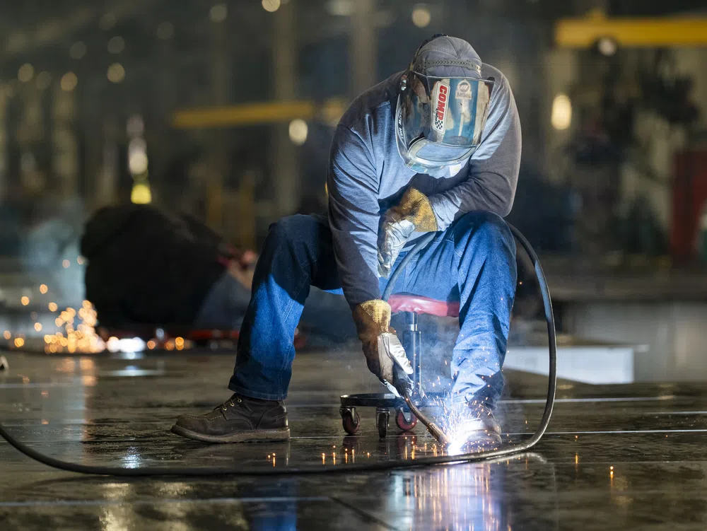 Welder wearing protective gear working with sparks flying in an industrial workshop setting