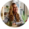 Smiling blonde woman with long hair sitting at a table during a casual meeting indoors.