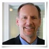 Middle-aged man in business attire smiling with blurred office background