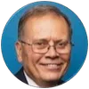 Portrait of a smiling elderly man with glasses against a blue circular background.