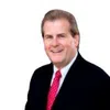 Rick Trainor in a suit smiling