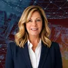 Smiling professional woman with blonde hair in navy blazer against a digital network and industrial background
