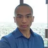 Man wearing blue shirt taking a selfie in front of a window with cityscape view in background