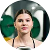 Young woman with hair tied back working out in gym with weightlifting equipment in background