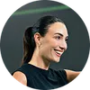 Smiling woman with ponytail wearing black sleeveless shirt in a fitness setting
