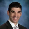 Professional man in dark suit and tie smiling against a blue textured background portrait