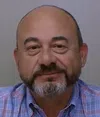 Middle-aged man with a bald head, salt-and-pepper beard, and plaid shirt against a neutral background.