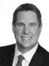 Smiling man in a suit and tie with short hair against a plain white background.