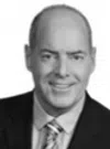 Portrait of a smiling bald man in a suit and patterned tie against a white background