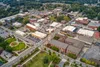 Aerial view of Lawrenceville with streets, buildings, church steeple, green park, and trees on a clear day.