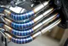 Close-up of polished exhaust pipes showcasing vibrant blue and silver finishes on a high-performance engine.