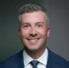 Smiling middle-aged man in business suit with gray hair against a plain background