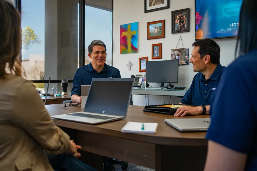 a group of people sitting at a table with laptops