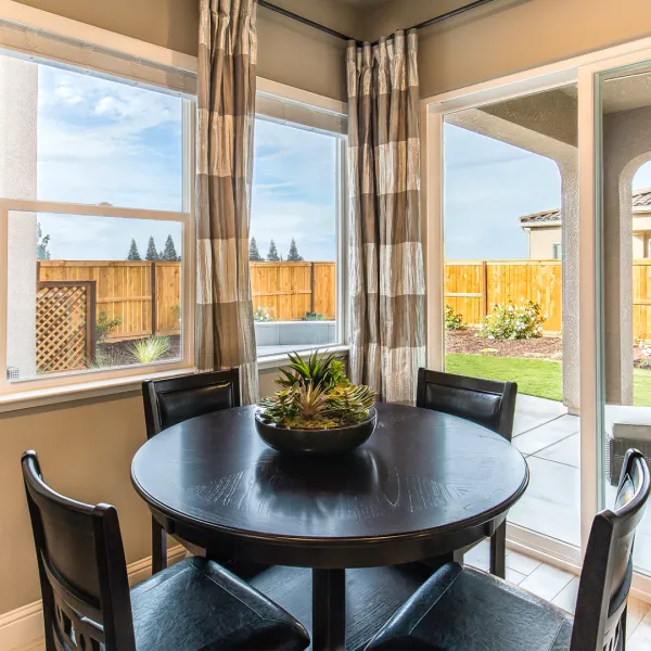 a table with chairs and a plant on it in front of a window
