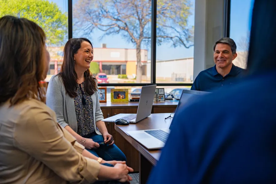 a group of people sitting at a table using a laptop computer