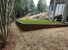 a yard with a brick wall and a grass lawn