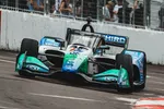 IndyCar race car speeding on track with green, white, and blue livery during a race event.