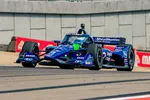 Blue IndyCar race car with ShipStation and Mobil 1 logos racing on a track with concrete barriers