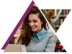 Young woman smiling and working on a laptop with a student browsing books in a library background.