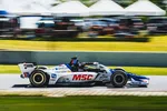 Side view of a white and blue race car with MSC logo speeding on a racetrack with blurred crowd background