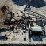 Aerial view of an industrial site with conveyor belts, machinery, gravel piles, and construction equipment.