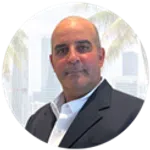 Professional man in a dark suit with a white shirt, city skyline and palm trees in the background.