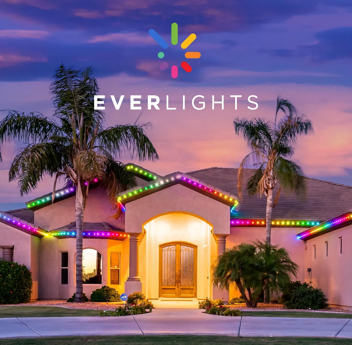 Modern house decorated with multicolor EverLights LED strip lights at dusk with palm trees and a purple sky.