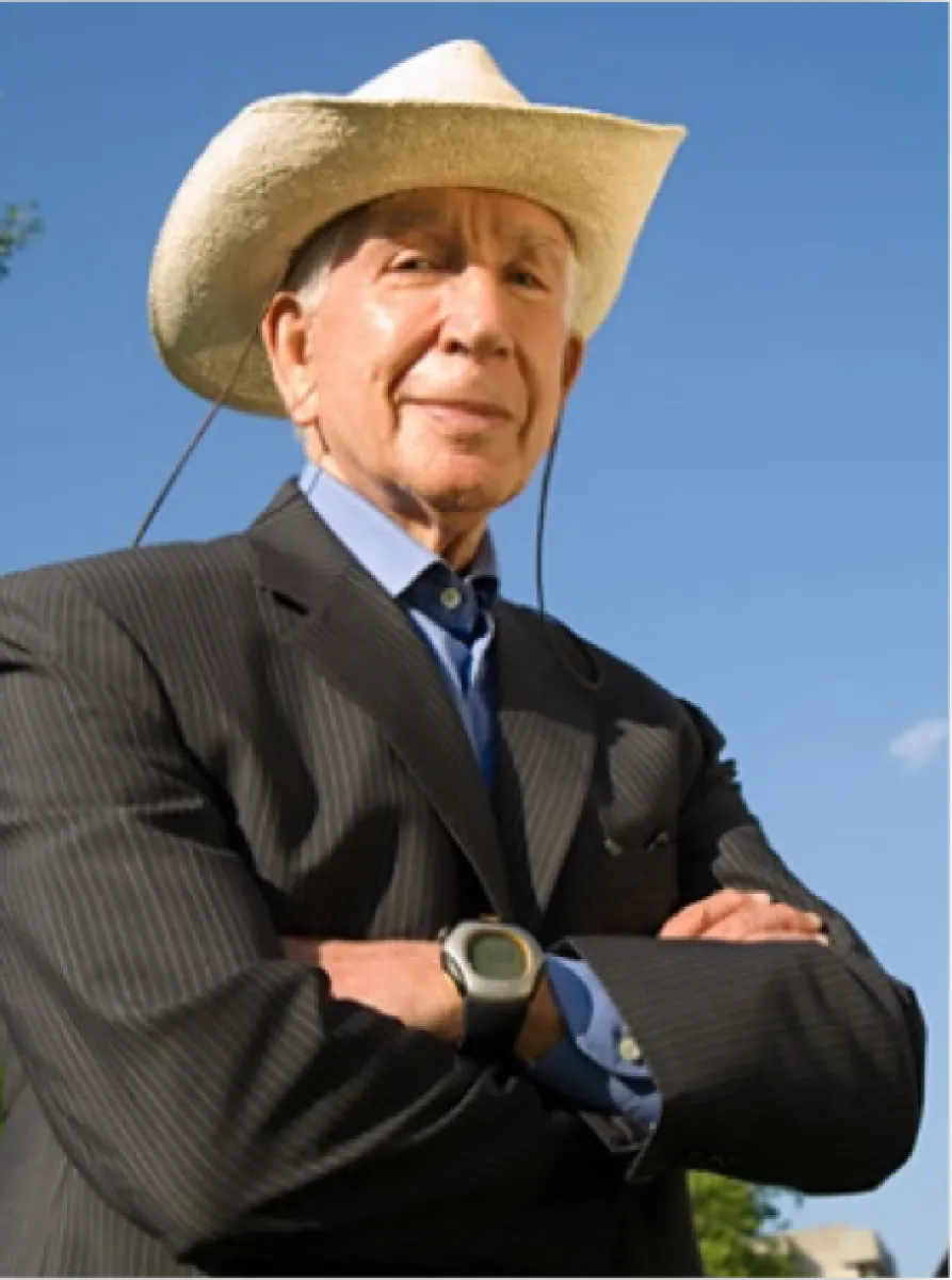 a man wearing a hat and a suit with his arms crossed