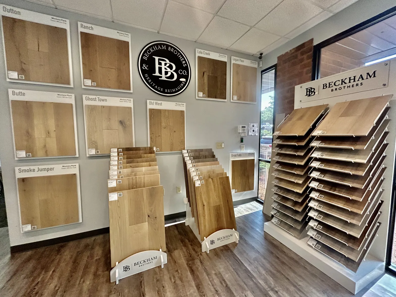 Beckham Brothers hardwood flooring samples displayed on racks and walls in a showroom with natural light.