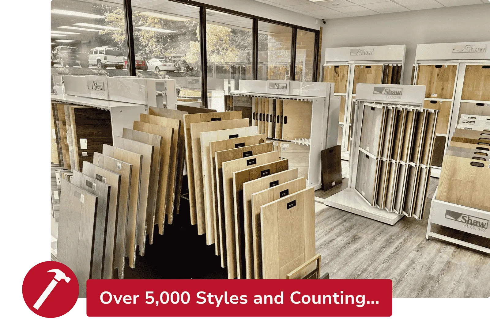 Showroom displaying various wooden flooring samples in natural light with large windows and organized racks.