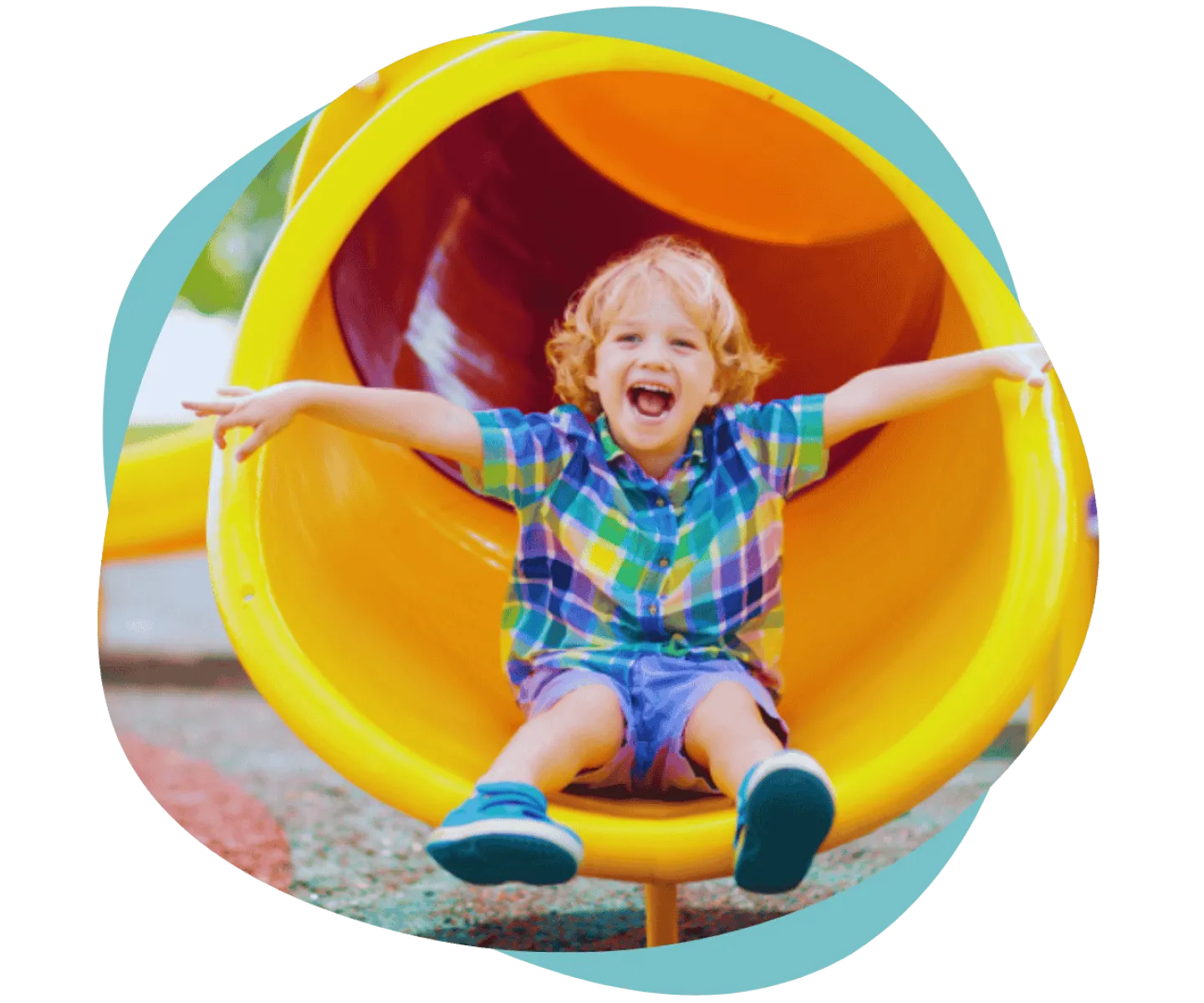 Happy young boy wearing colorful plaid shirt sliding down a bright yellow playground tube slide outdoors.
