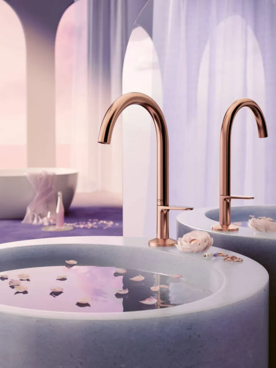 Modern bathroom with a round stone sink filled with water and rose petals, rose gold faucet, and soft purple lighting.