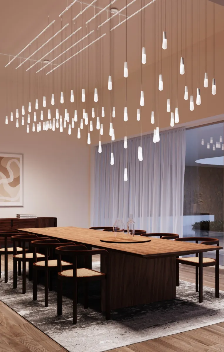 Modern dining room with large wooden table, dark chairs, hanging pendant lights, abstract art, and glass wall.