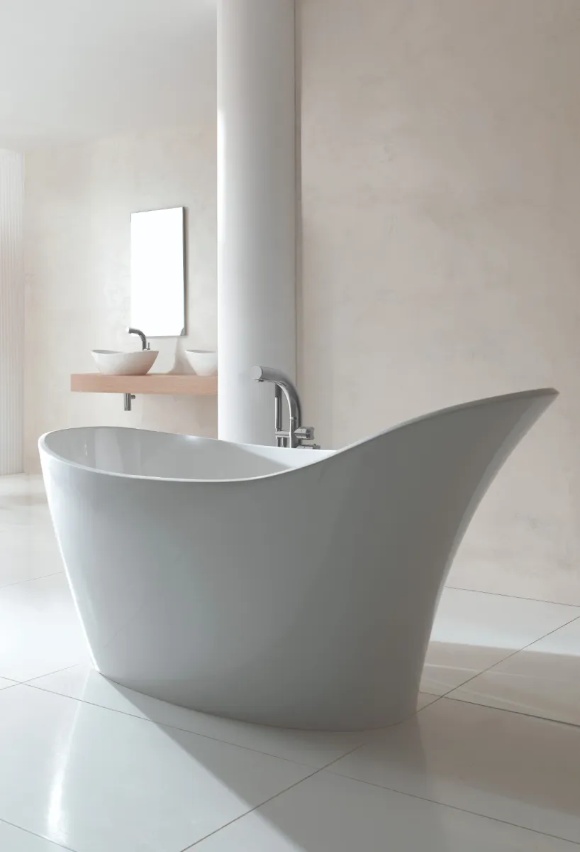 Modern white freestanding bathtub in a minimalist bathroom with sleek fixtures and wooden chair seating.