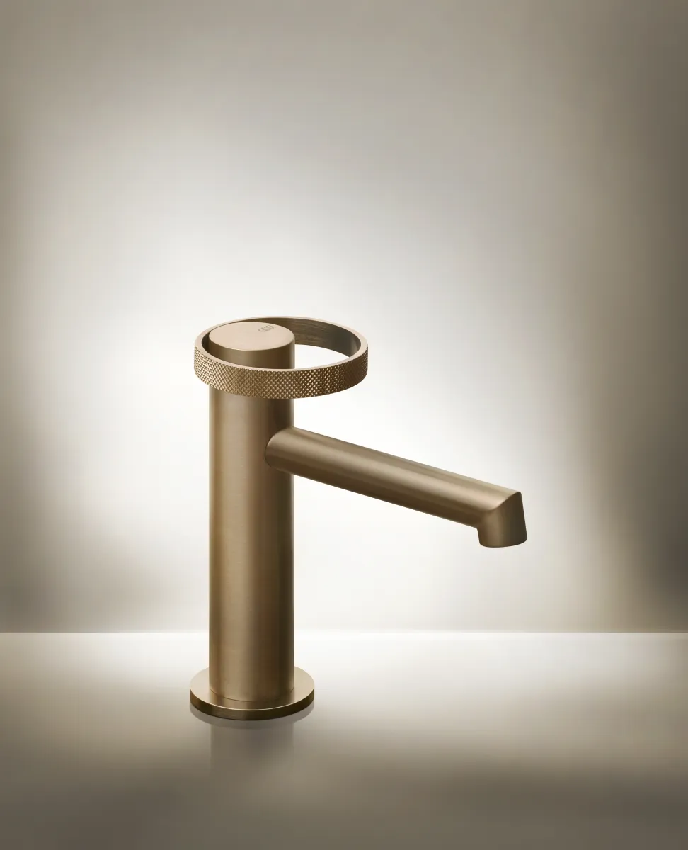 Modern matte bronze bathroom faucet with a unique textured circular handle on a clean surface.