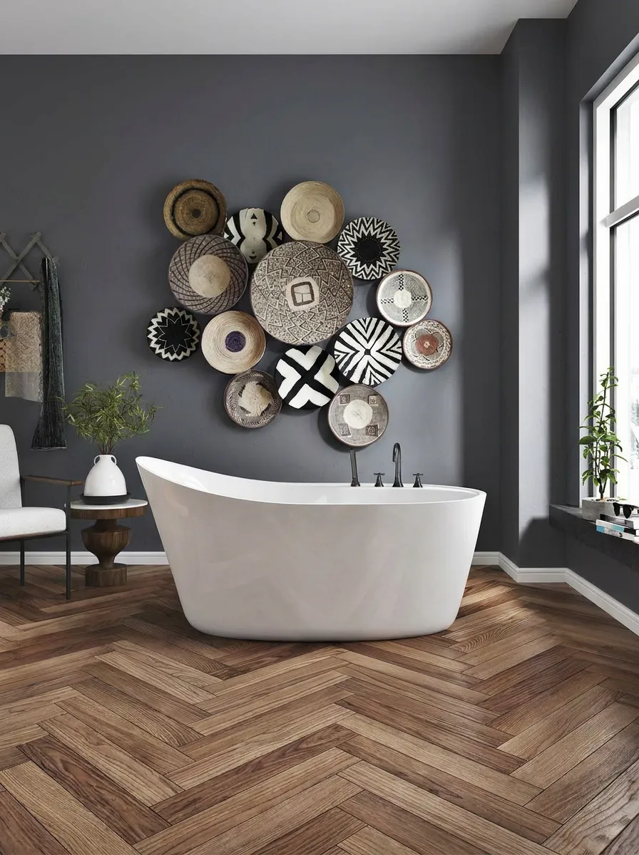 Modern bathroom with white freestanding tub, dark gray walls, decorative woven baskets, and wood herringbone floor