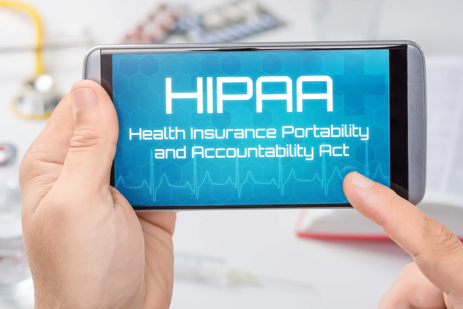 Hands holding a smartphone displaying HIPAA Health Insurance Portability and Accountability Act text with medical background.