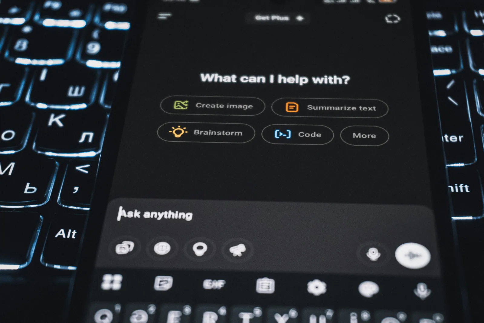 Smartphone screen showing AI assistant options on a dark interface over a backlit keyboard.