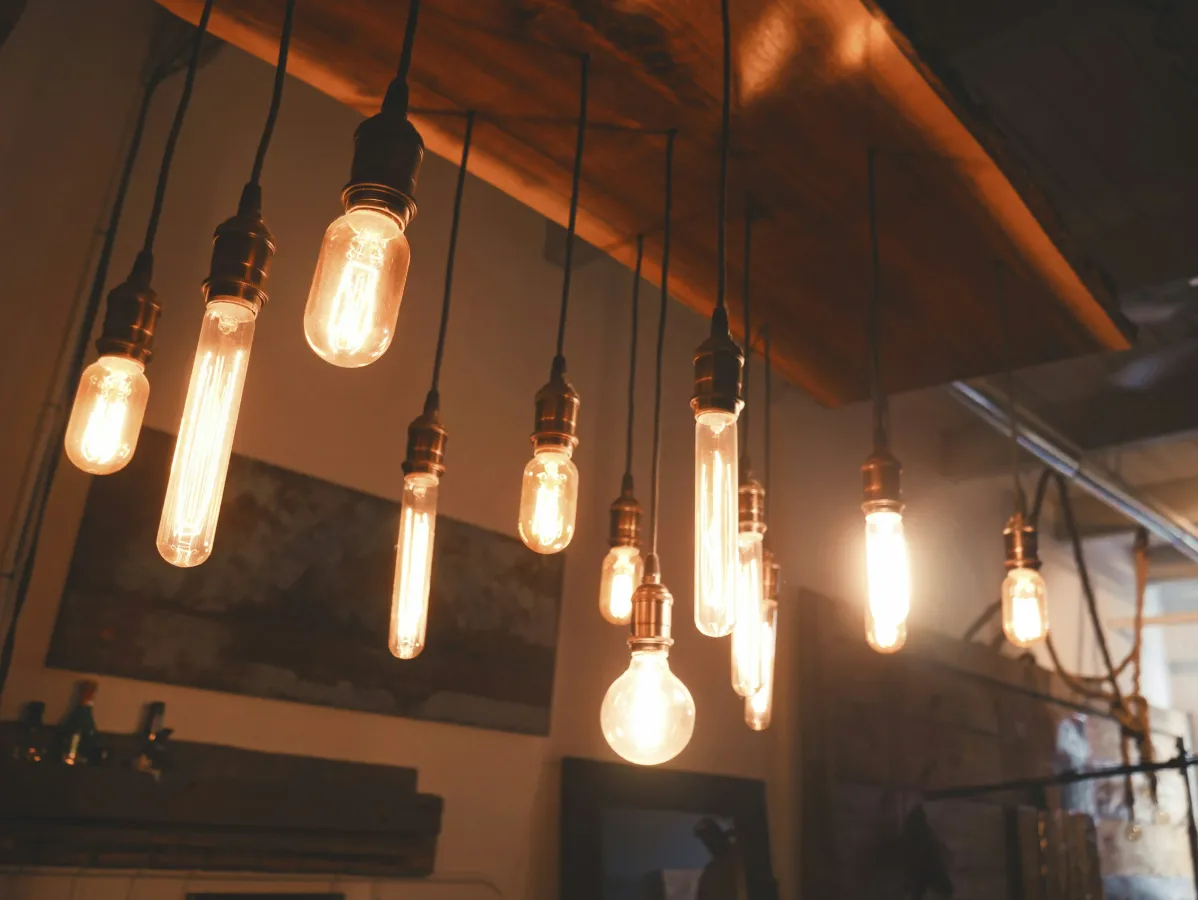 Warm glowing vintage Edison light bulbs hanging from a wooden ceiling fixture in a cozy room.