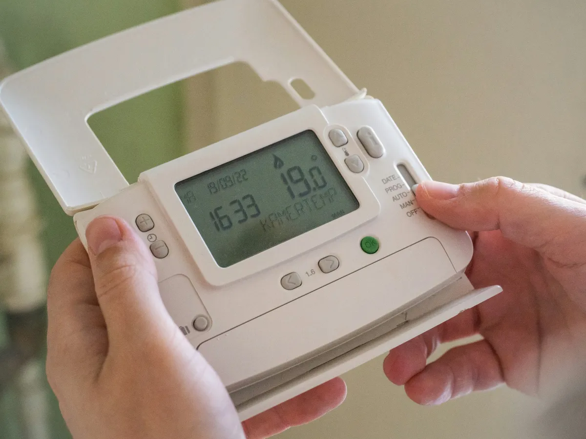 a person holding a home thermostat