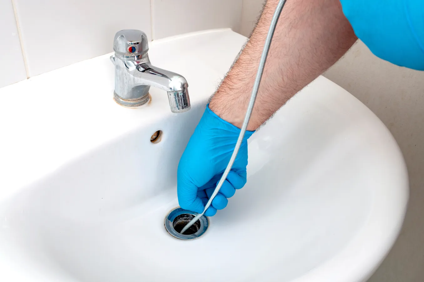 a person's arm with a blue glove on a sink