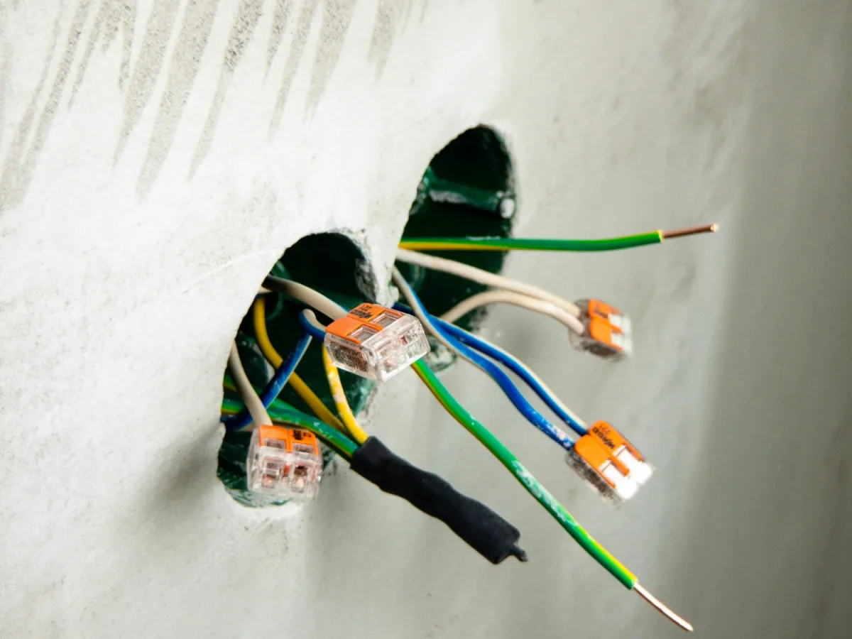 Exposed electrical wires with connectors protruding from a wall during installation or repair work.