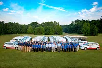 a group of people posing for a photo in front of cars