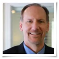 Middle-aged man in business attire smiling with blurred office background