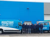 Advantage Plumbing & Sewer Co. team stands in front of company vans outside a building with a blue wall.