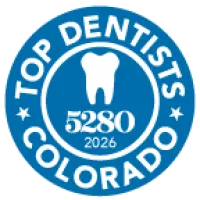 Blue circular badge with white tooth icon, text Top Dentists Colorado, number 5280, and year 2026.
