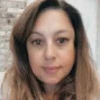 Close-up of a woman with long brown hair, natural makeup, and a neutral background.